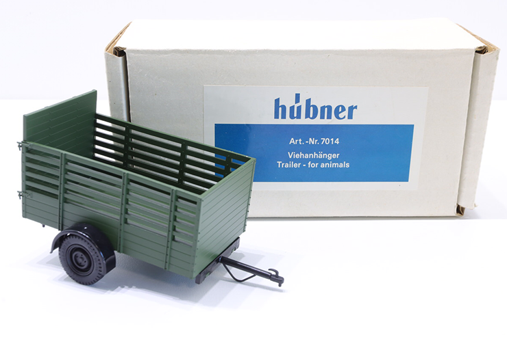 Spur 1 Modell eines grünen Einachs-Viehanhängers von Hübner Feinmechanik (Art. 7014), abgebildet vor dem weißen Originalkarton.